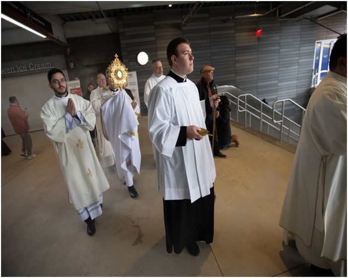 Biskop Brennan bär det heliga sakramentet och monstransen under en eukaristisk procession på Louis Armstrong Stadium