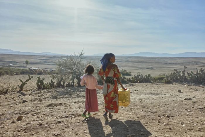 En kvinna och en flicka i Tigray går med förnödenheter.