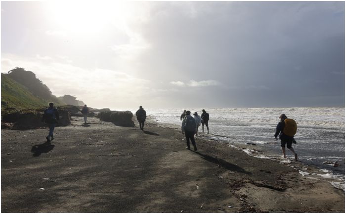 Pilgrimer vandrar längs stranden under en pilgrimsfärd organiserad av Modern Catholic Pilgrim.