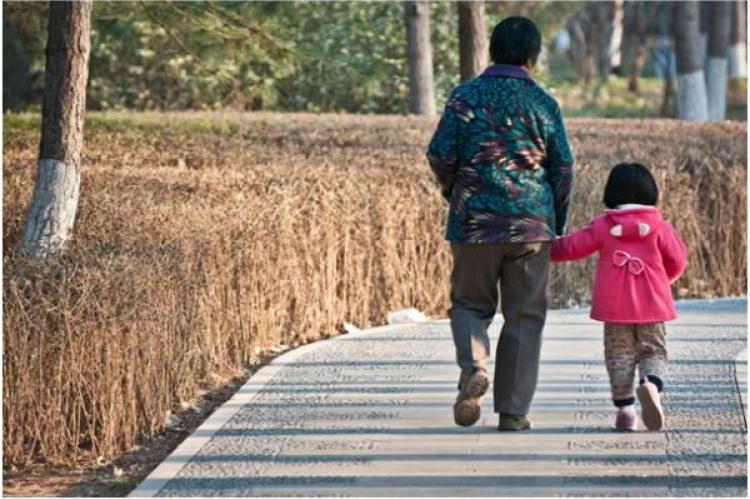 En äldre kinesisk kvinna är ute och går med barnbarnet