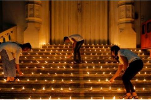 Ungdomar tänder ljus framför den stängda dörren till en kyrka i Colombo