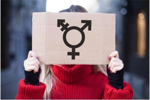 En kvinna visar plakat med symbol för könsöverskridande identitet. Från Shutterstock