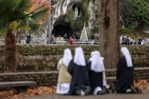 Nuns pray near the Massabielle cave in the Sanctuary of Lourdes, south-western France on November 7, 2022.