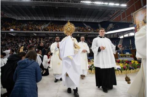 Biskop Robert Brennan leder en eukaristisk procession inne på ett fullsatt Louis Armstrong Stadium i Brooklyn