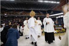 Biskop Robert Brennan leder en eukaristisk procession inne på ett fullsatt Louis Armstrong Stadium i Brooklyn